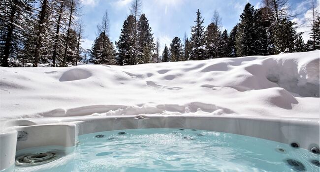 Ein Jacuzzi inmitten einer idyllischen Winterlandschaft mit Schnee und Wald