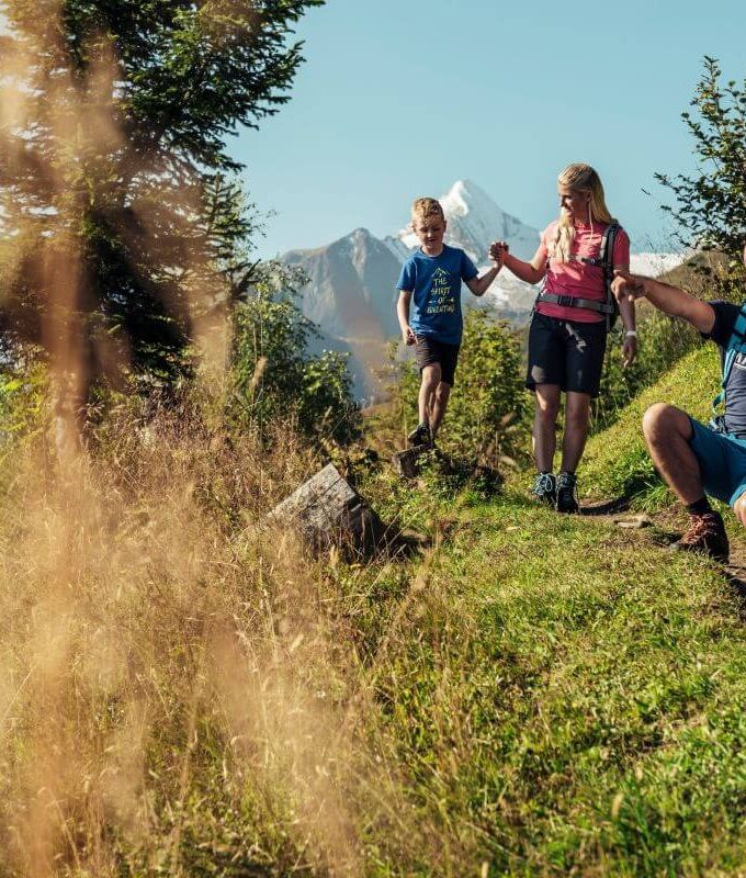 A family with two children takes a short break on the Maiskogel, with the Kitzsteinhorn in the background.