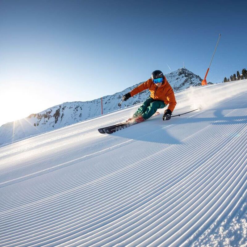 Skiers making a carving turn on the freshly groomed piste