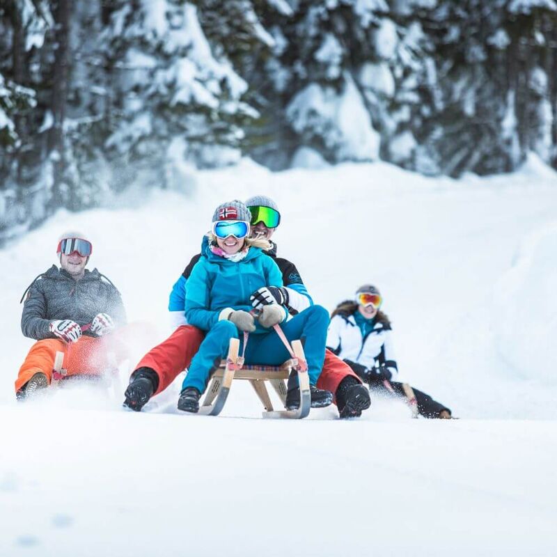 Gruppe von Freunden beim Rodeln im verschneiten Wald