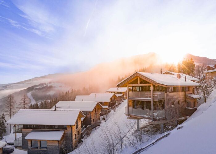 Holiday homes and chalets in a snowy winter landscape and sunrise