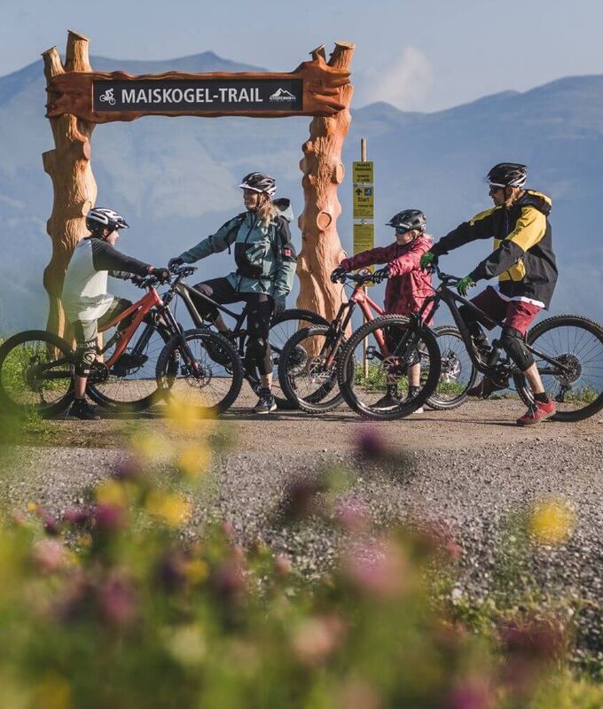 Family with two children and their bikes at the start of a bike trail.