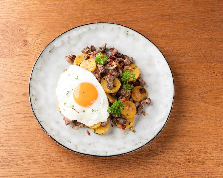 Teller mit Tiroler Gröstl und Spiegelei auf einem Küchentisch