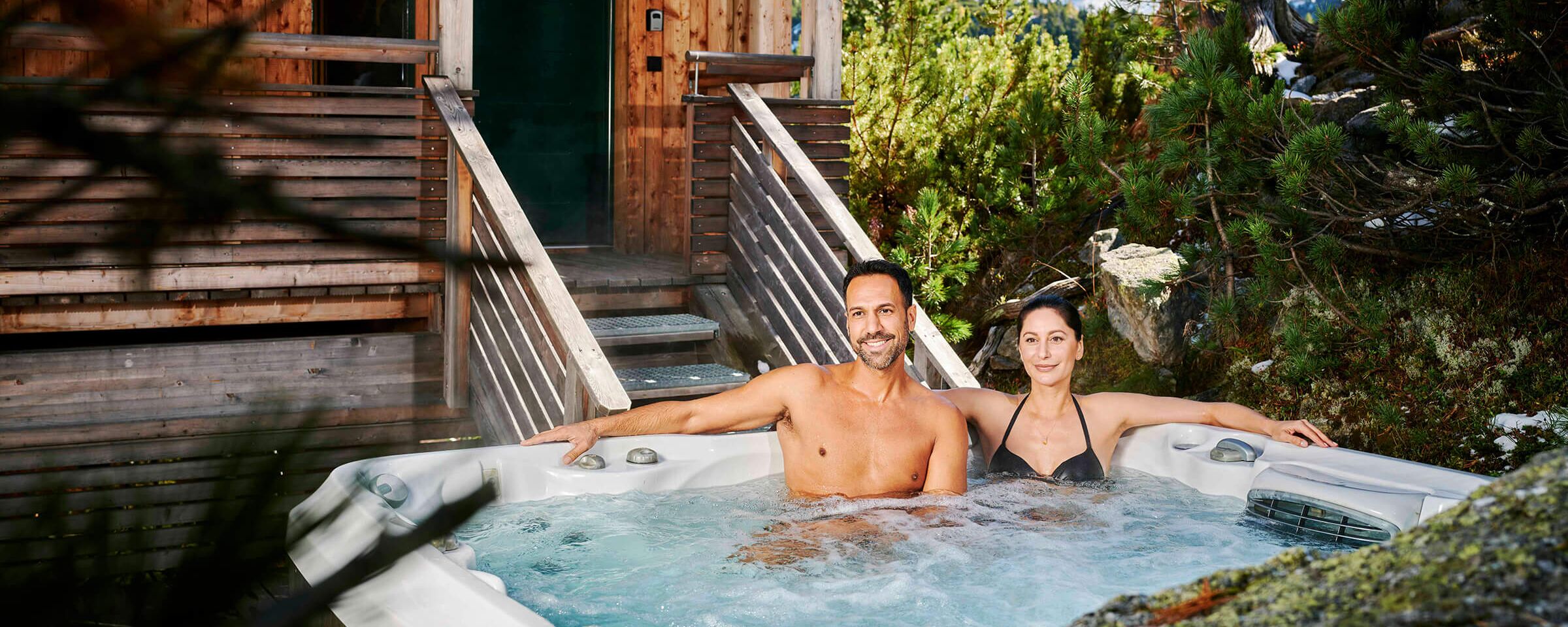 Menschen im Whirlpool vor einem Ferienhaus im Herbst