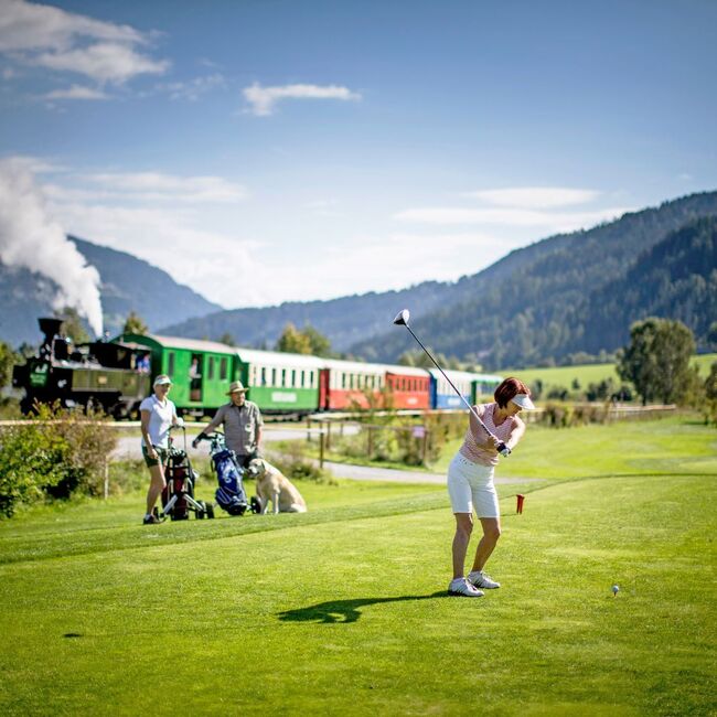 Golferin am Golfplatz, im Hintergrund die Murtalbahn