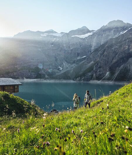 A hiker at the upper Kaprun high mountain reservoir, surrounded by high alpine terrain.