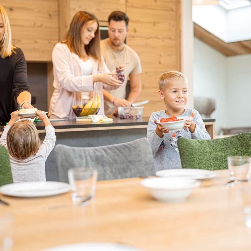 Oma, Eltern und 2 Kinder bereiten ihr Frühstück in der Ferienwohnung zu.