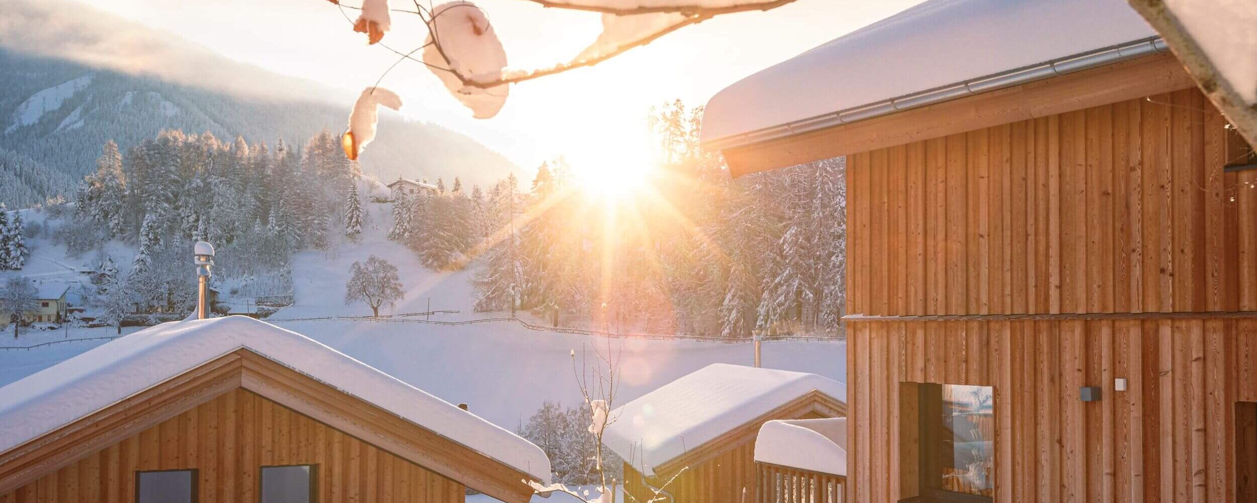 Winterlandschaft mit viel Schnee und drei Ferienhäuser im Tiroler Chalet-Stil