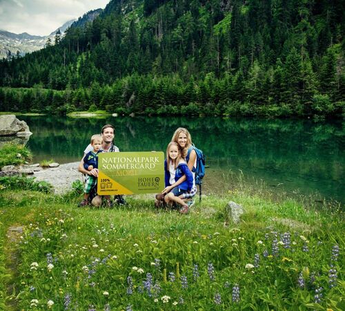 Family with 2 children with the National Park Summer Card at a mountain lake
