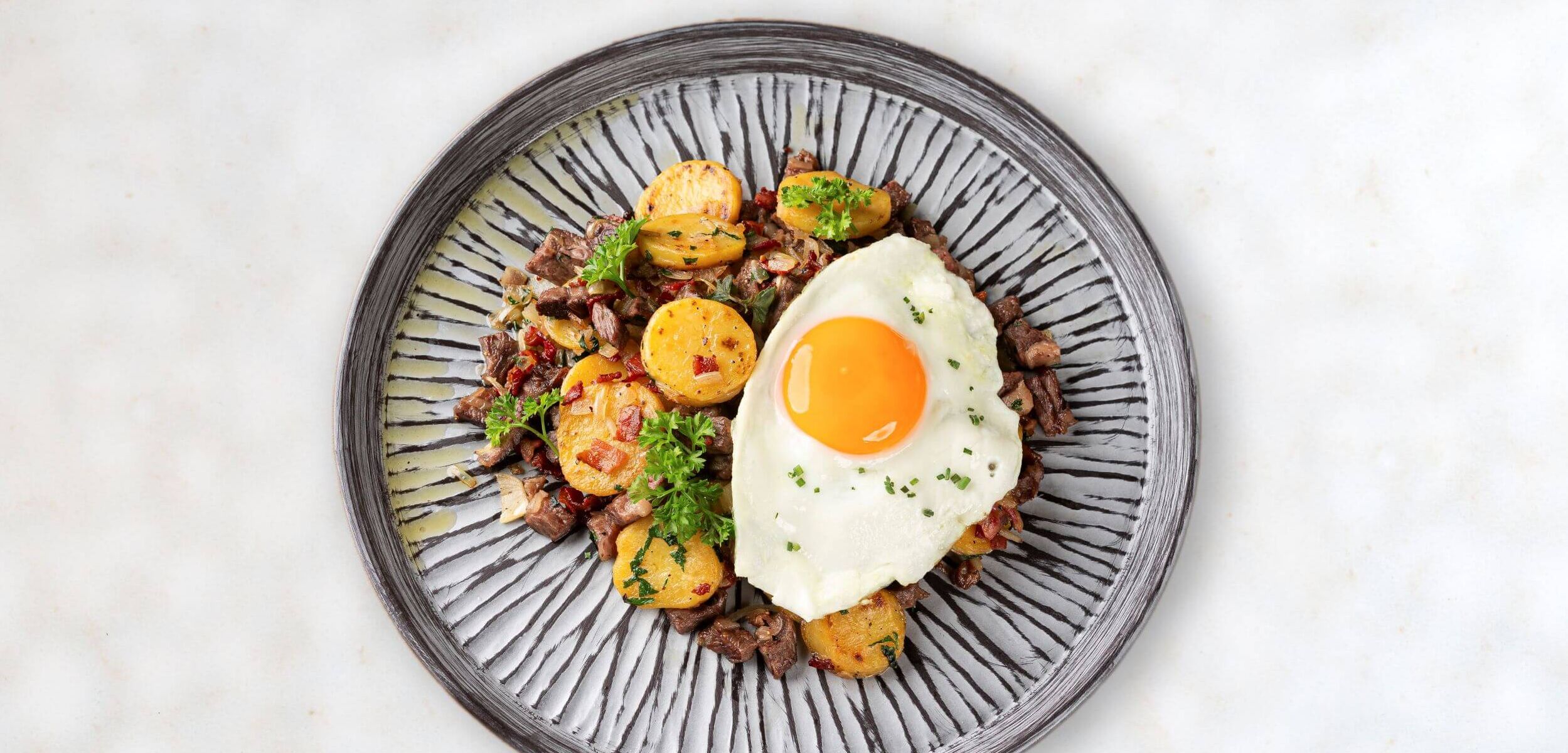 Teller voll Tiroler Gröstl mit Spiegelei und Rindfleisch