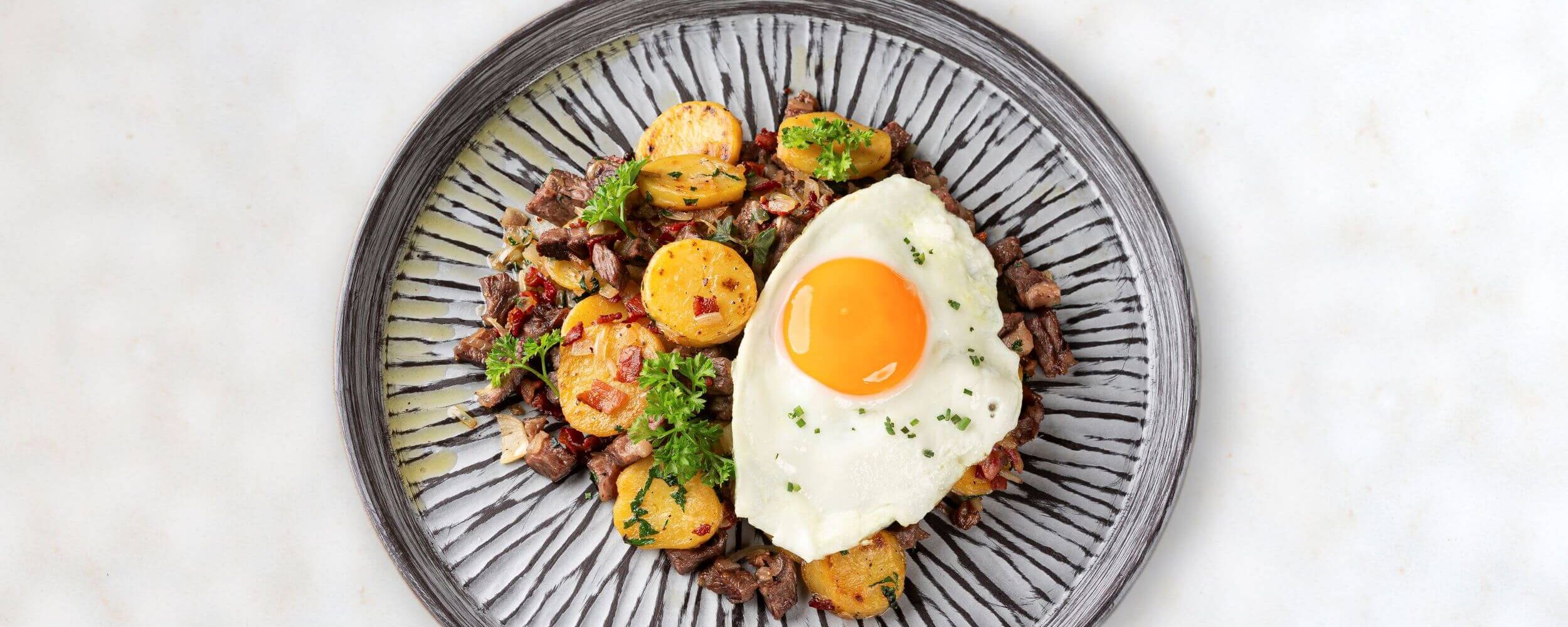 Plate full of Tyrolean Gröstl with fried egg and beef