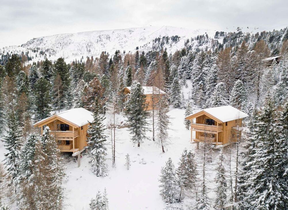 Wooden vacation homes in the wintry Swiss stone pine forest on the Turracher Höhe