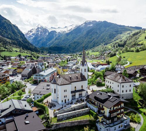 View from above of Kaprun’s village centre with its church, with the Kitzsteinhorn rising in the background.