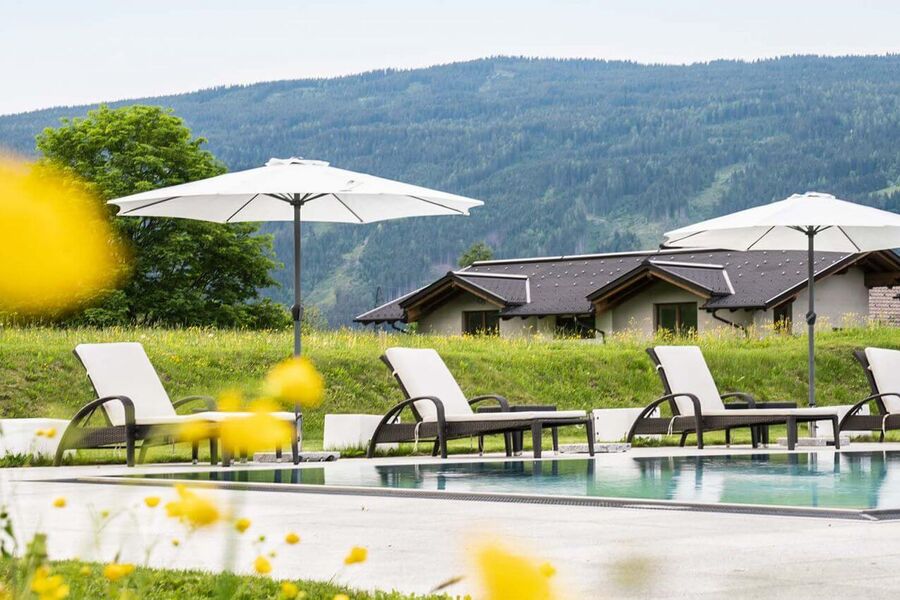 Outdoor Pool mit Sonnenliegen und Schirmen in der Tauernresidence Radstadt