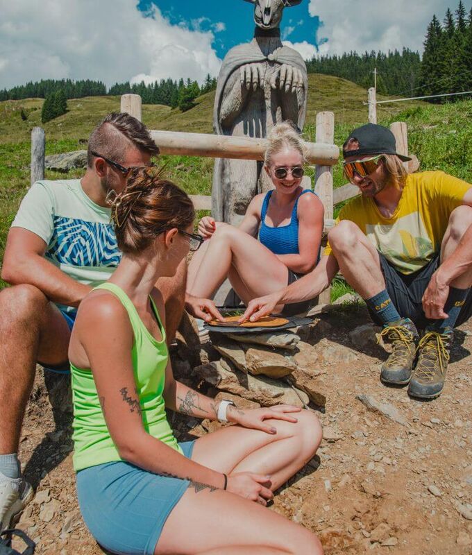 Four teenagers puzzle over a challenge at a station on the Escape Trail "Mystery Queens" in Saalbach.