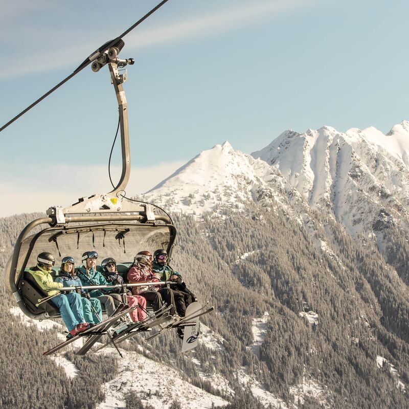 Skiers at the lift and blue sky and mountain in the background