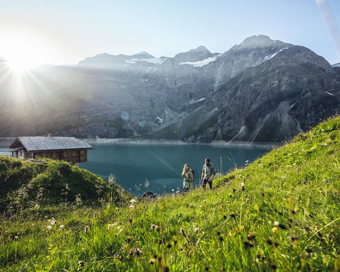 Wanderer am oberen Kapruner Hochgebirgsstausee vor hochalpinem Gelände.