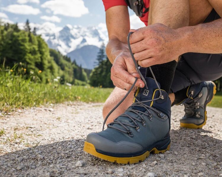 Ein Mann beim Binden seiner Salomon Bergschuhe