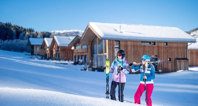 Skifahrer stehen im tiefen Schnee vor den Ferienhäusern