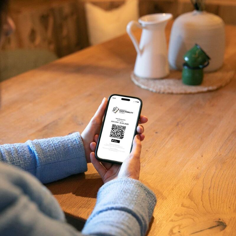 Frau hält ihr Handy mit dem Guest Mobility Ticket in der Hand.
