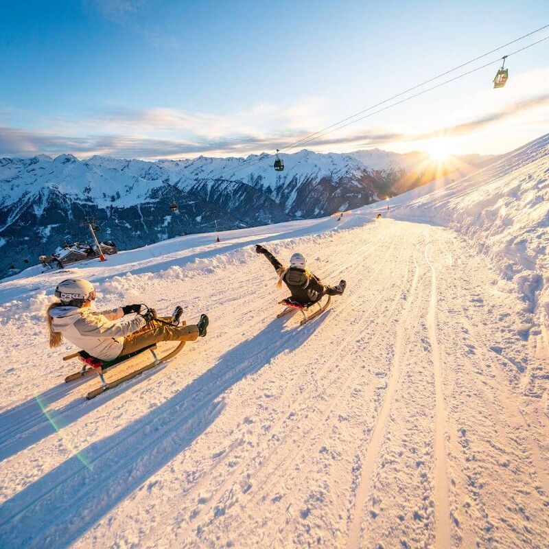 Zwei Schlittenfahrerinnen bei der Abfahrt auf der Wildkogel Rodelbahn
