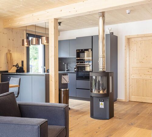 Offener Küchenblock mit moderner Ausstattung und Kamin mit Sichtfenster