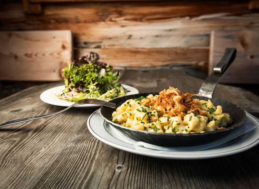 Käsespätzle mit braunem Butter und Zwiebeln in der gusseisernen Pfanne