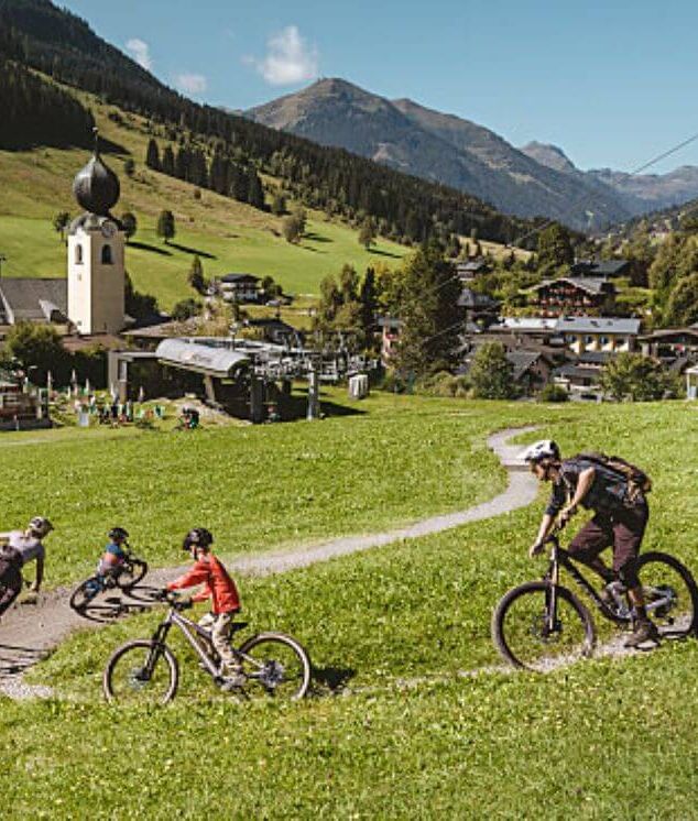 A family rides their bikes on one of the trails in the Learn to Ride Park in Saalbach.