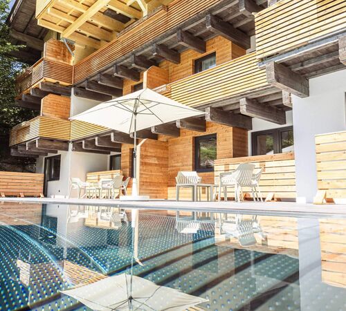 Außenpool auf der Terrasse mit gemütlichen Liegen, Sitzbereichen und Sonnenschirmen für entspannte Wellnessmomente