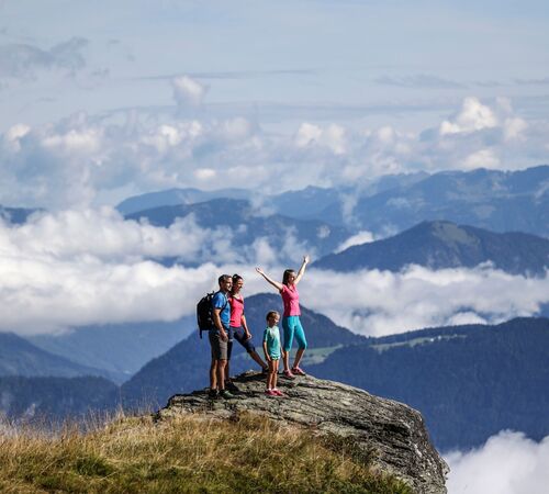 Familie genießt bei Wanderungen in den Tiroler Alpen eine herrliche Aussicht auf die umliegende Bergwelt mit grünen Hügeln und Wäldern