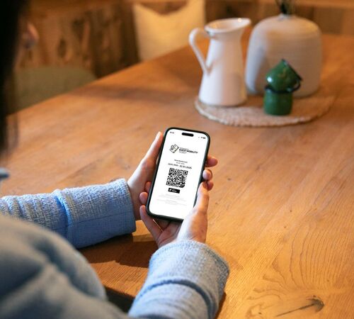 Woman holding her mobile phone with the Guest Mobility Ticket.