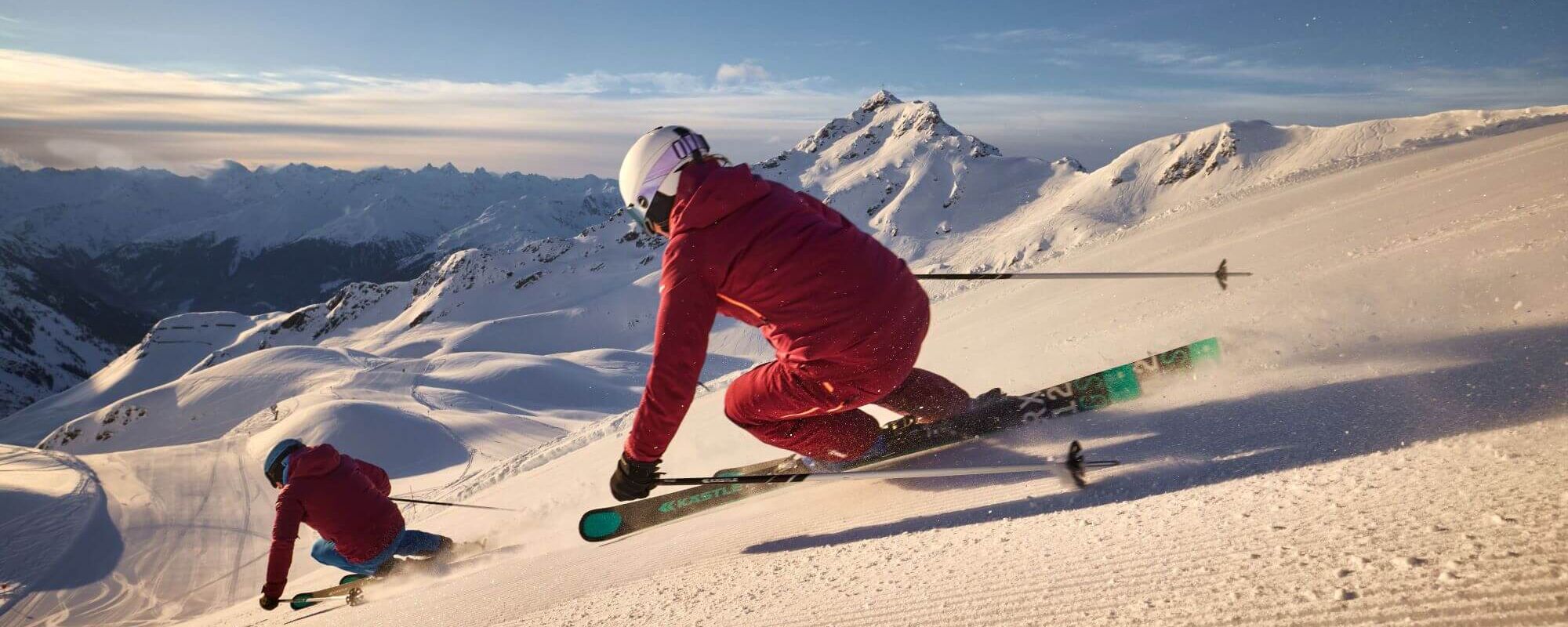 2 Skifahrer carven eine lange Abfahrt auf der frisch präparierten Piste im Skigebiet Silvretta-Montafon hinunter.