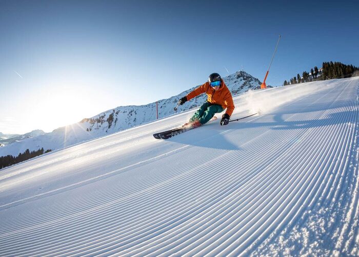 Skifahrer beim Carving Schwung auf der "schneesicheren Seite des Kitzbüheler Horns": St. Johann in Tirol