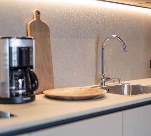 Beige, moderne Küchenzeile mit Spülbecken, Filterkaffeemaschine und Holzschneidebrett