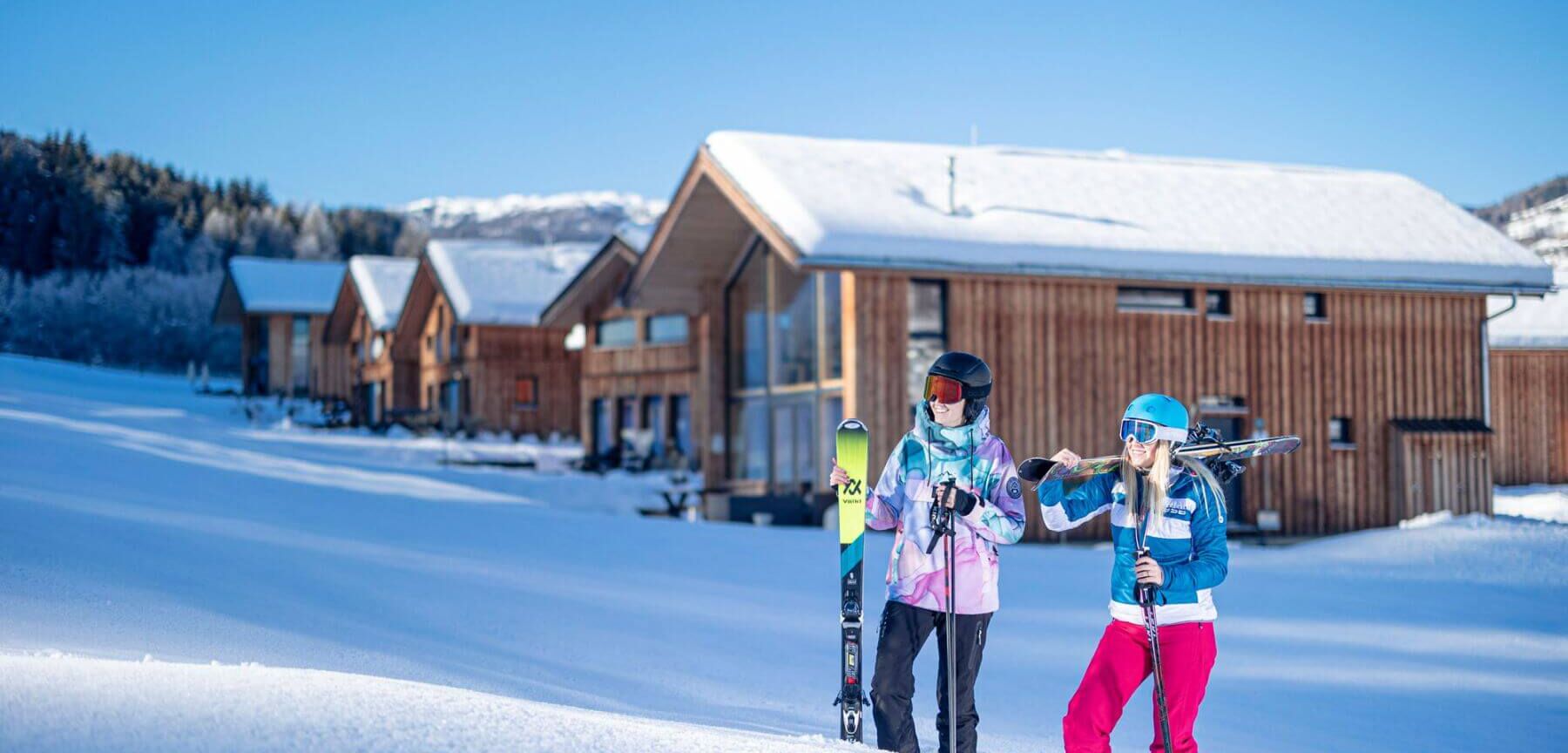 Skifahrer stehen im tiefen Schnee vor den Ferienhäusern