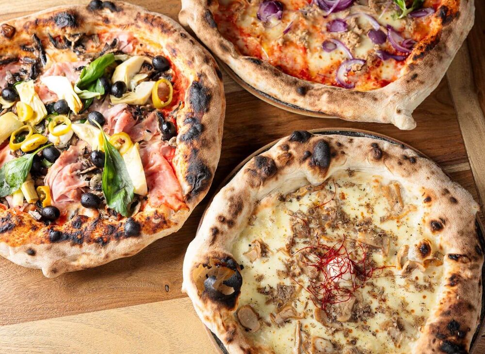 Three fresh Neapolitan pizzas are served at mangia! Saalbach are served.
