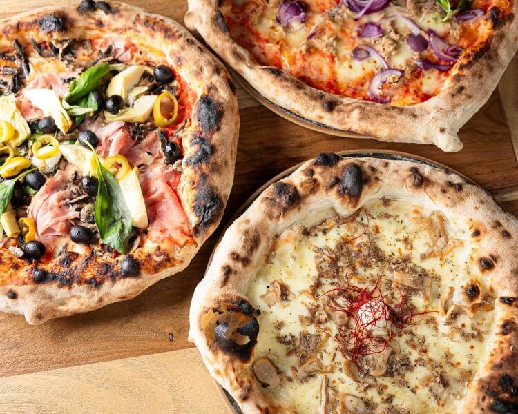 Drei neapolitanische frische Pizzen werden im mangia! Saalbach serviert.