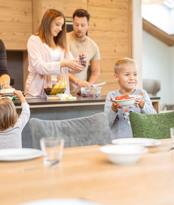 Oma, Eltern und 2 Kinder bereiten ihr Frühstück in der Ferienwohnung zu.