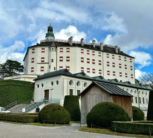 Schloss Ambras mit rot weiss roten Fensterläden, umgeben von gepflegten Gärten