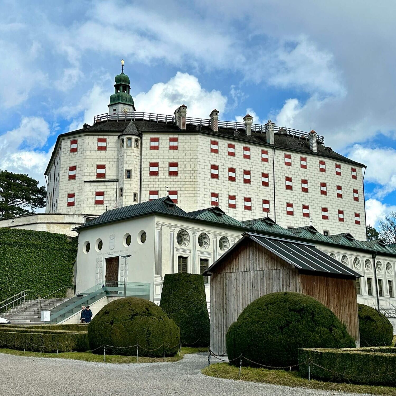 Schloss Ambras mit rot-weiss-roten Fensterläden, umgeben von gepflegten Gärten