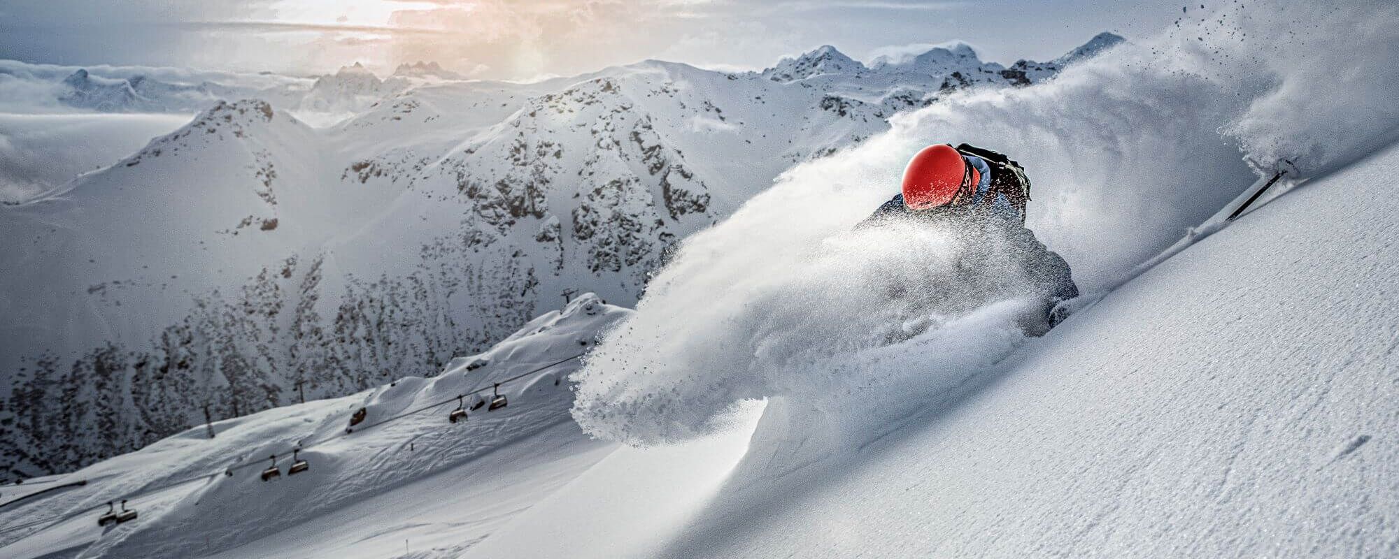 Freeriders descending in powder snow, with a modern chairlift in the background