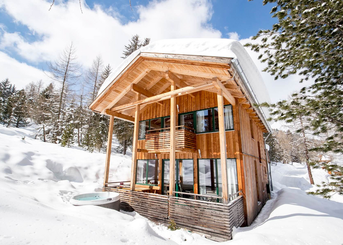 Ferienhaus in Schnee bedeckter Waldlandschaft und Hot-Tub