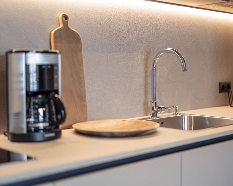 Beige, moderne Küchenzeile mit Spülbecken, Filterkaffeemaschine und Holzschneidebrett