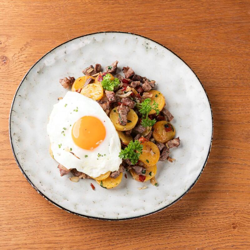 Teller mit Tiroler Gröstl und Spiegelei auf einem Küchentisch