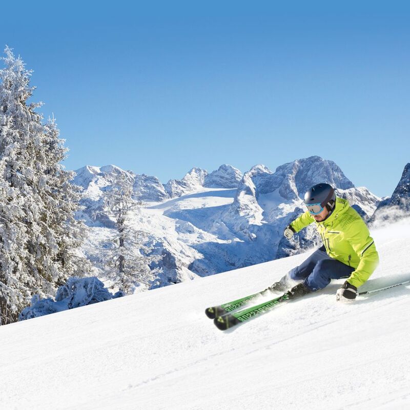 Skier on his descent with a view of the snow-covered mountains and trees