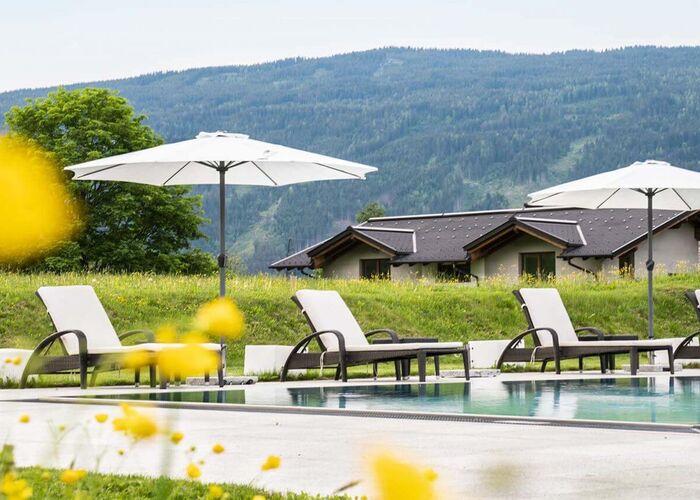 Outdoor-Pool mit Sonnenliegen und Schirmen in der Tauernresidence Radstadt