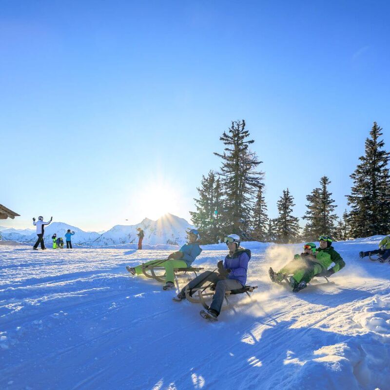 Gruppe von Rodlern fahren die präparierte Hochwurzen Rodelbahn hinunter.
