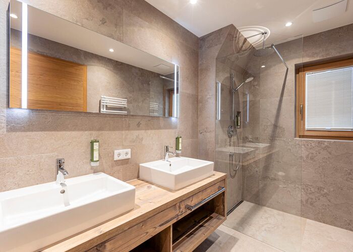 Zwei Waschbecken, großer Spiegel und eine Duschkabine in einem Bad mit modernen Wohlfühlstil