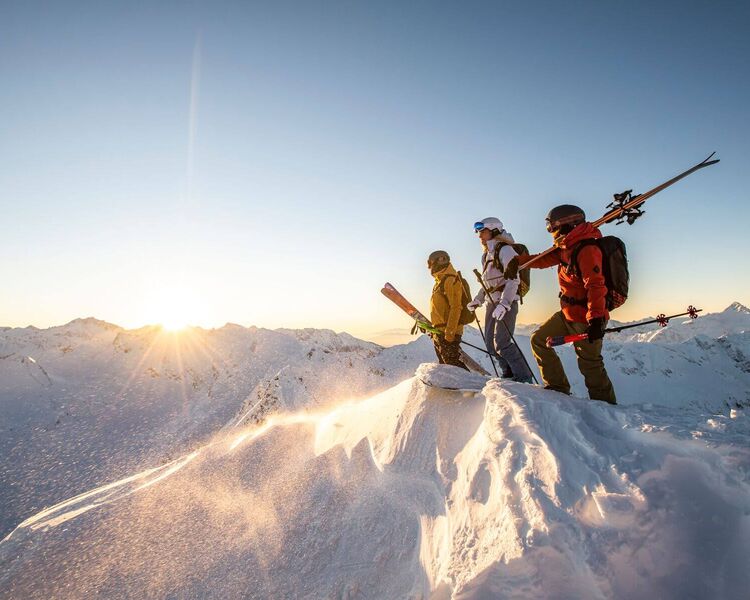 Skifahrer auf verschneiten Gipfel mit herbstlicher Lichtstimmung