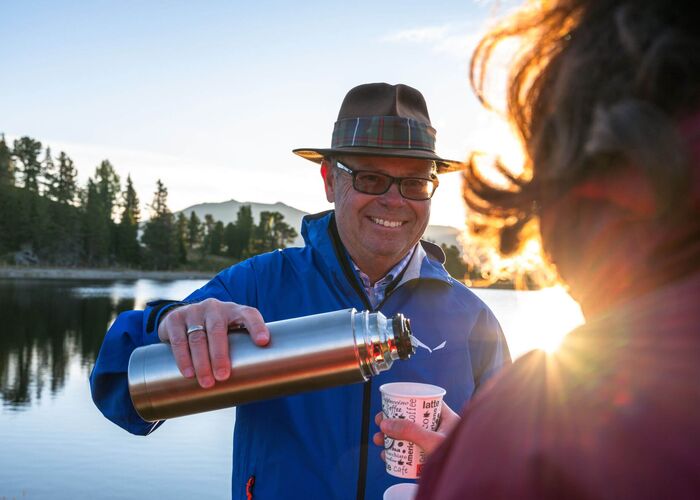 Almbutler serviert Tee bei Sonnenuntergang